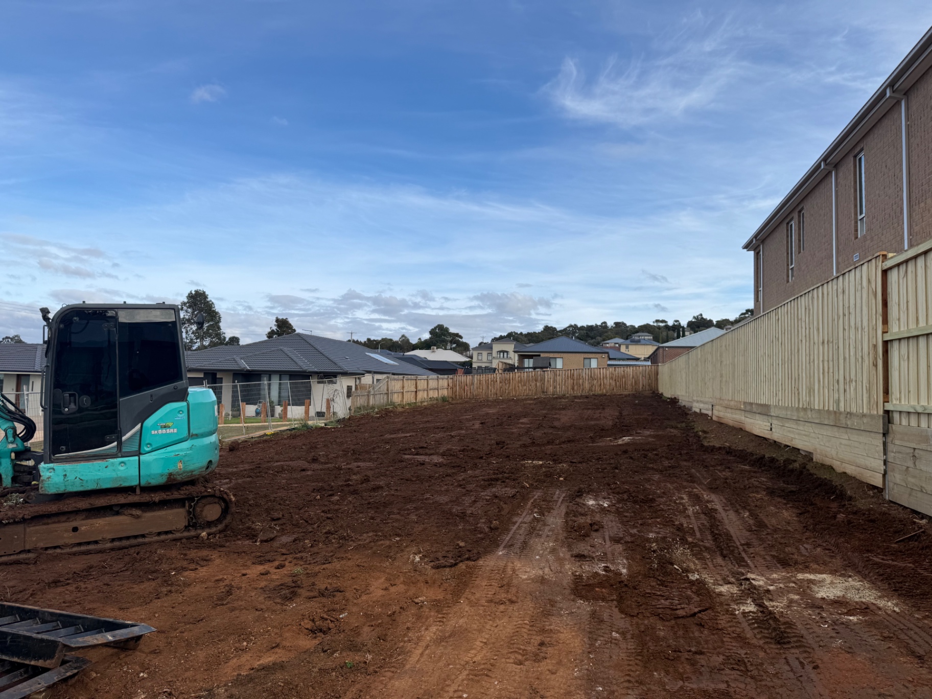 Completed subdivision road and earthworks under a blue sky